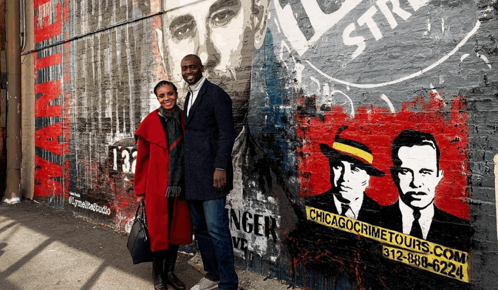 couple standing in front of a mural on a chicago crime tour