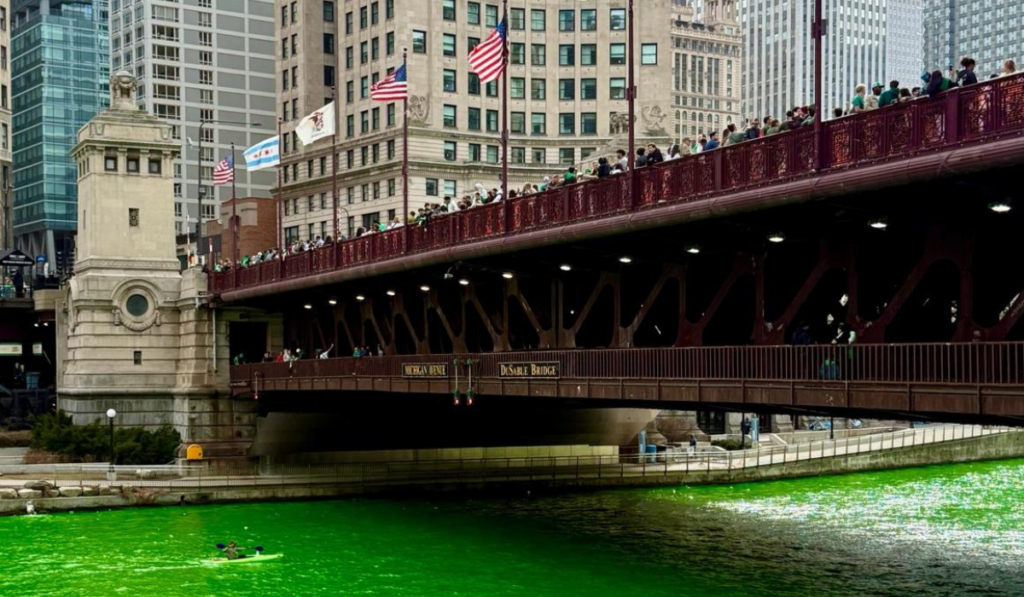 green river flowing under a bridge in chicago with parade watchers standing on the bridge