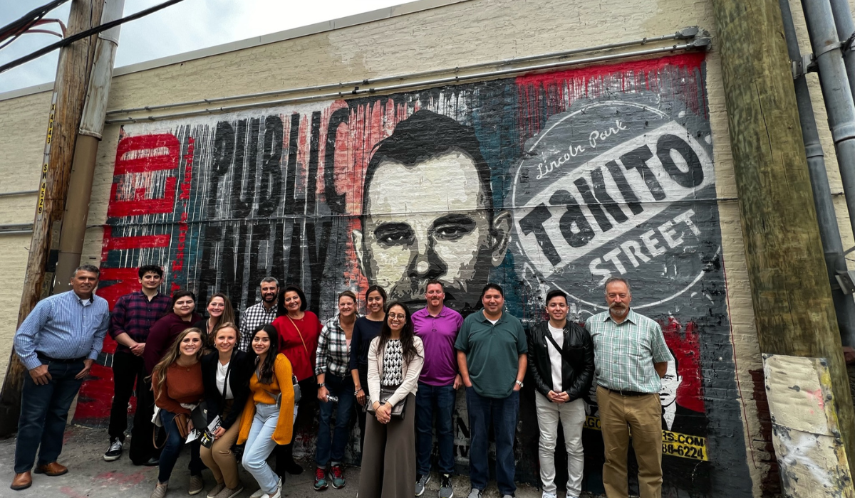corproate group standing in front of the mural at john dillinger alley on a chicago crime tour