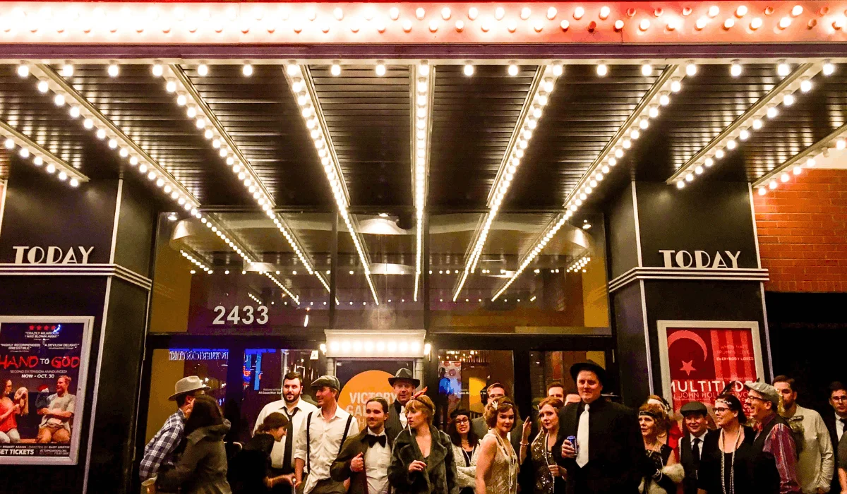 group of people in prohibition era clothing standing outside the biograph theater